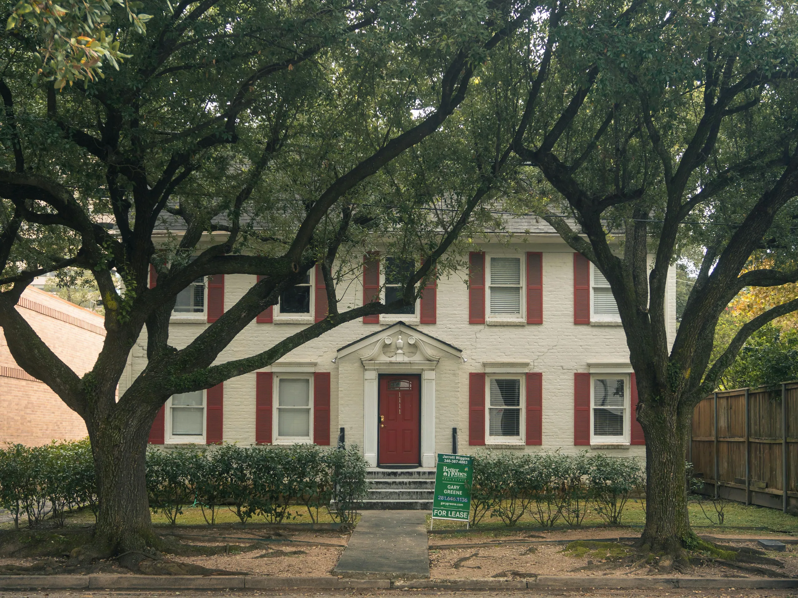 A traditional brick home framed by mature oak trees