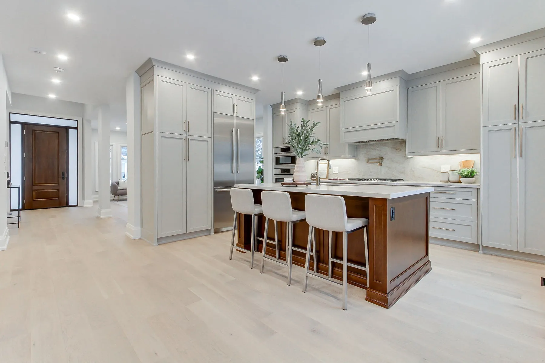 A modern kitchen with pale grey cabinetry and a walnut-panel island with white stone counter