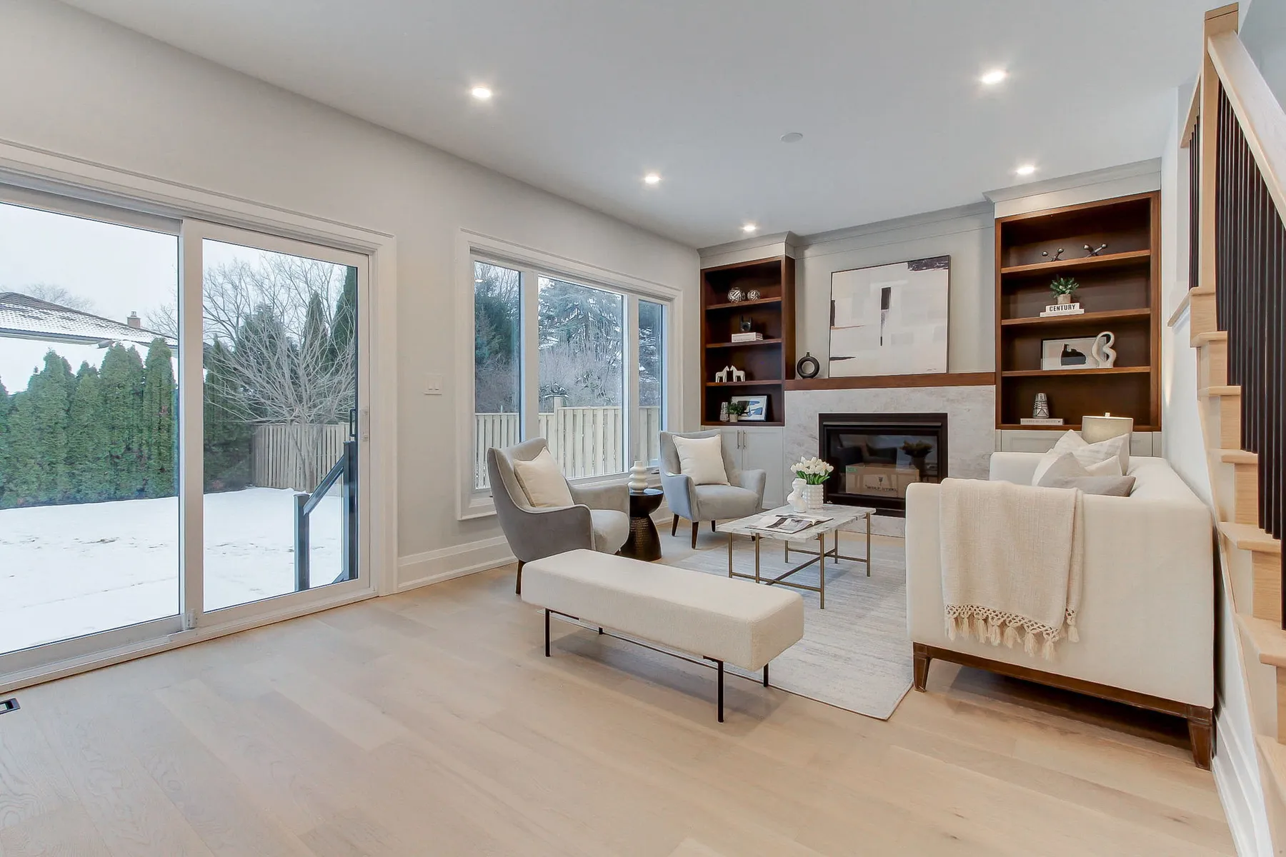 A family room with a gas fireplace flanked by dark wood built-in shelving