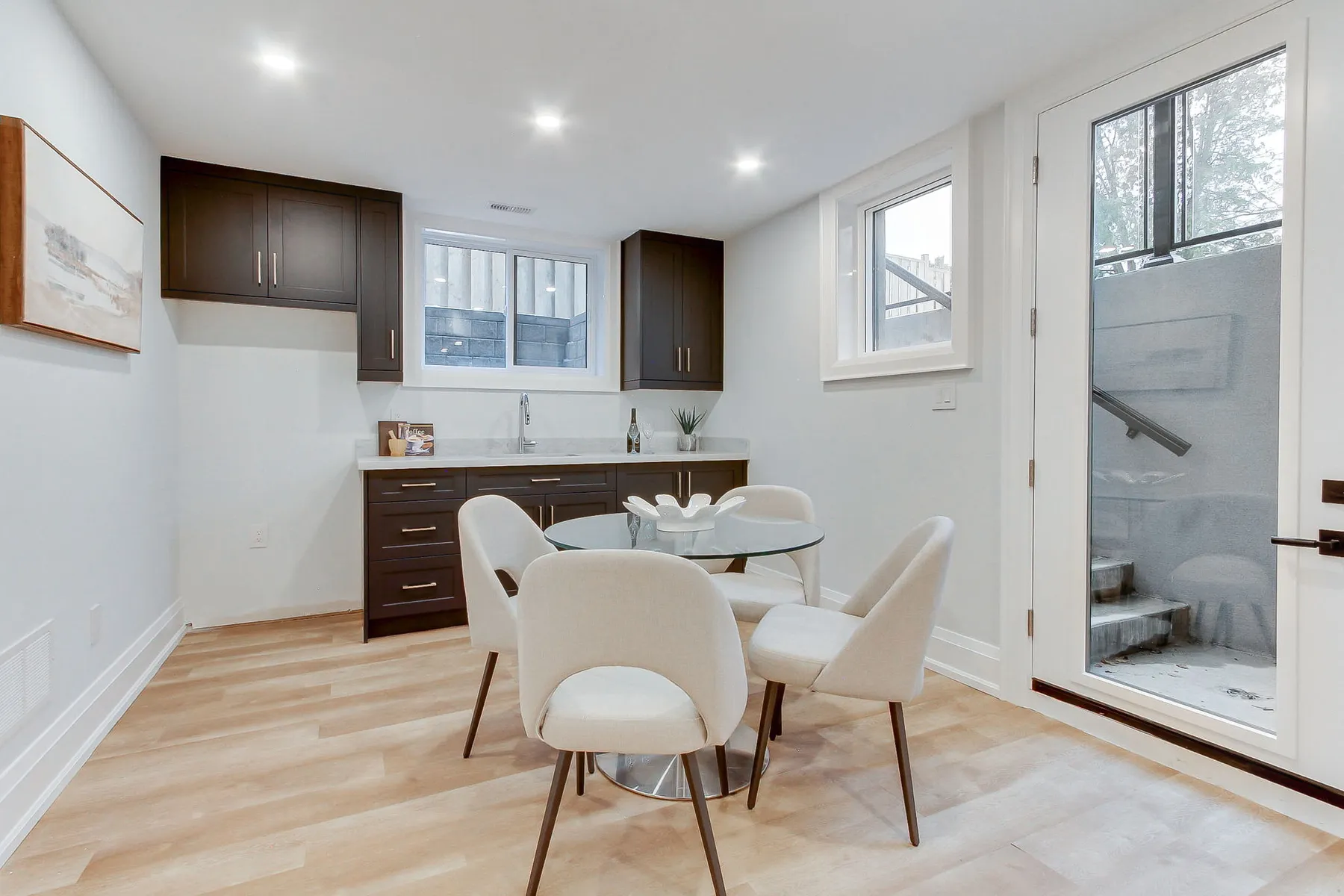 A finished lower-level suite with a kitchenette in dark cabinetry and a walkout door