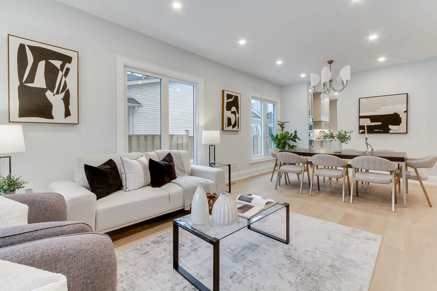 An open living and dining area with light oak floors, a cream sofa and a dark wood dining table