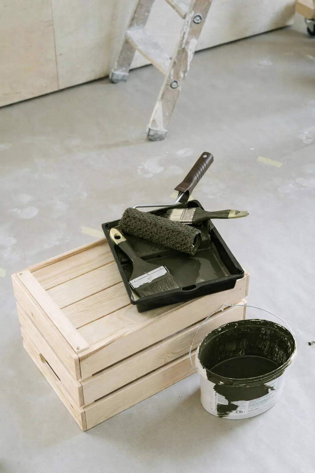 A roller tray of forest-green paint with a wooden crate during a renovation